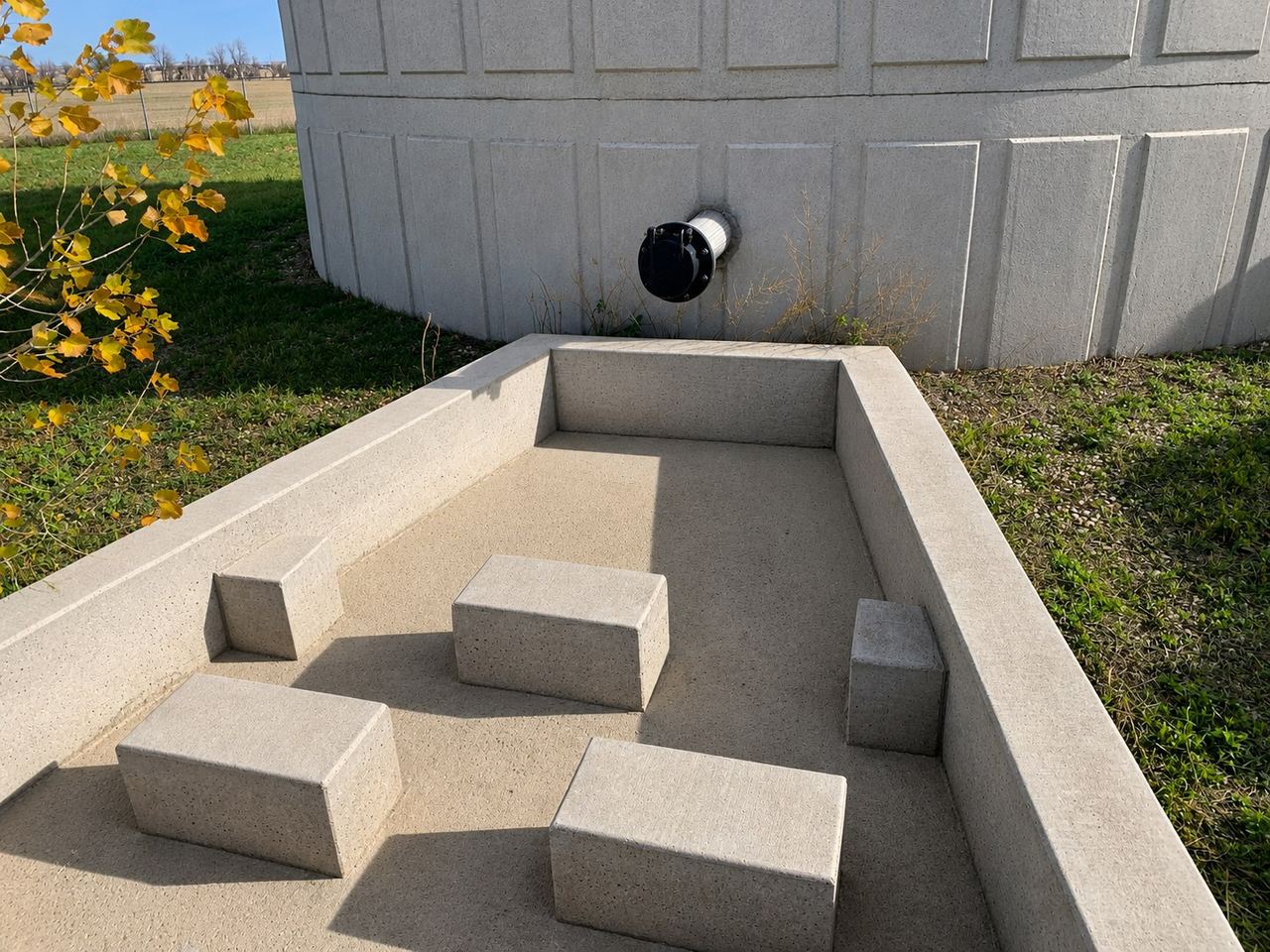 Concrete secondary containment basin beside a chemical storage tank