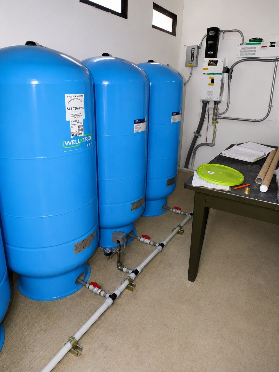 Bank of three blue hydropneumatic pressure tanks in a pump house