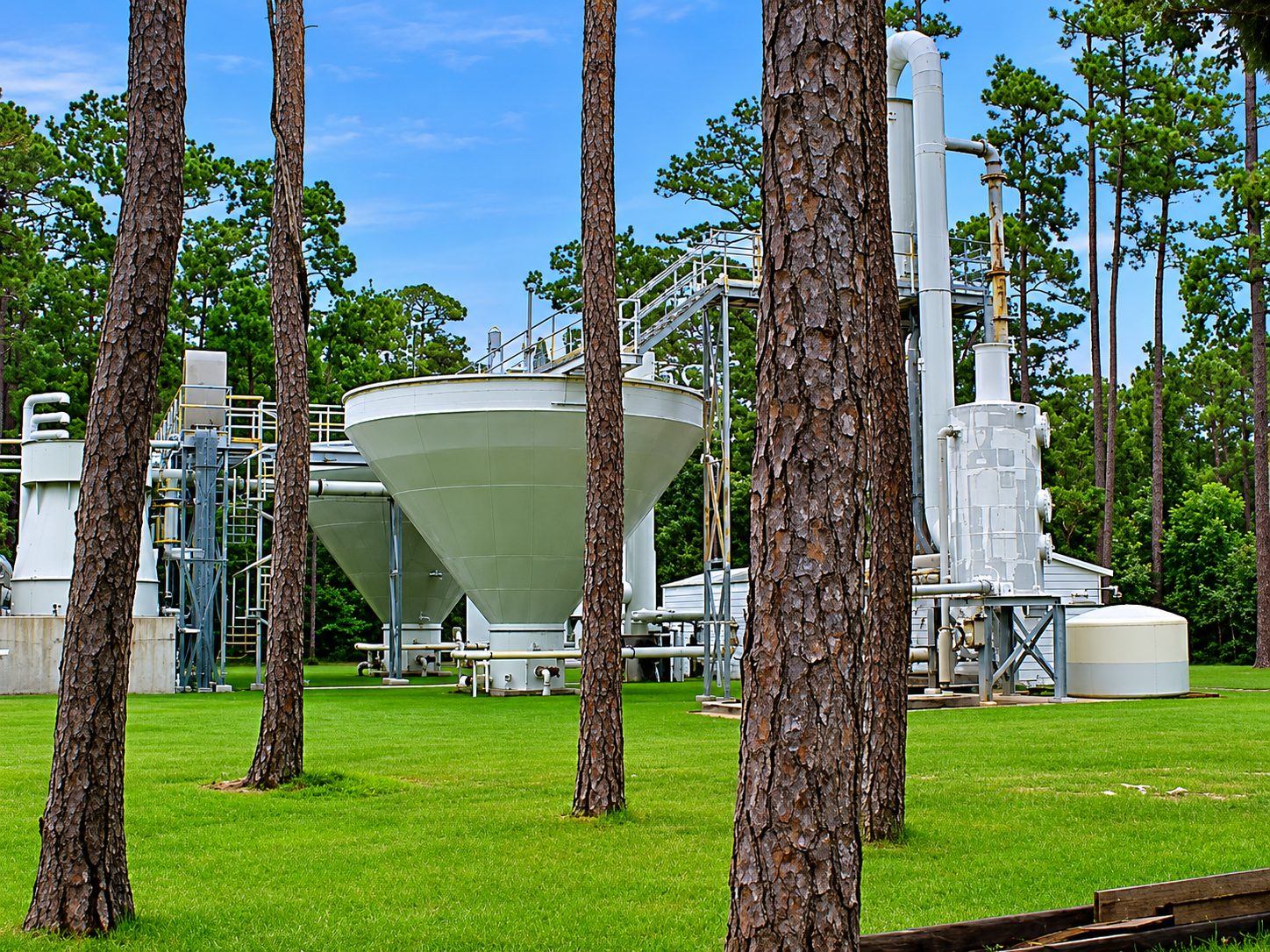 Water treatment plant filtration tanks surrounded by tall pine trees